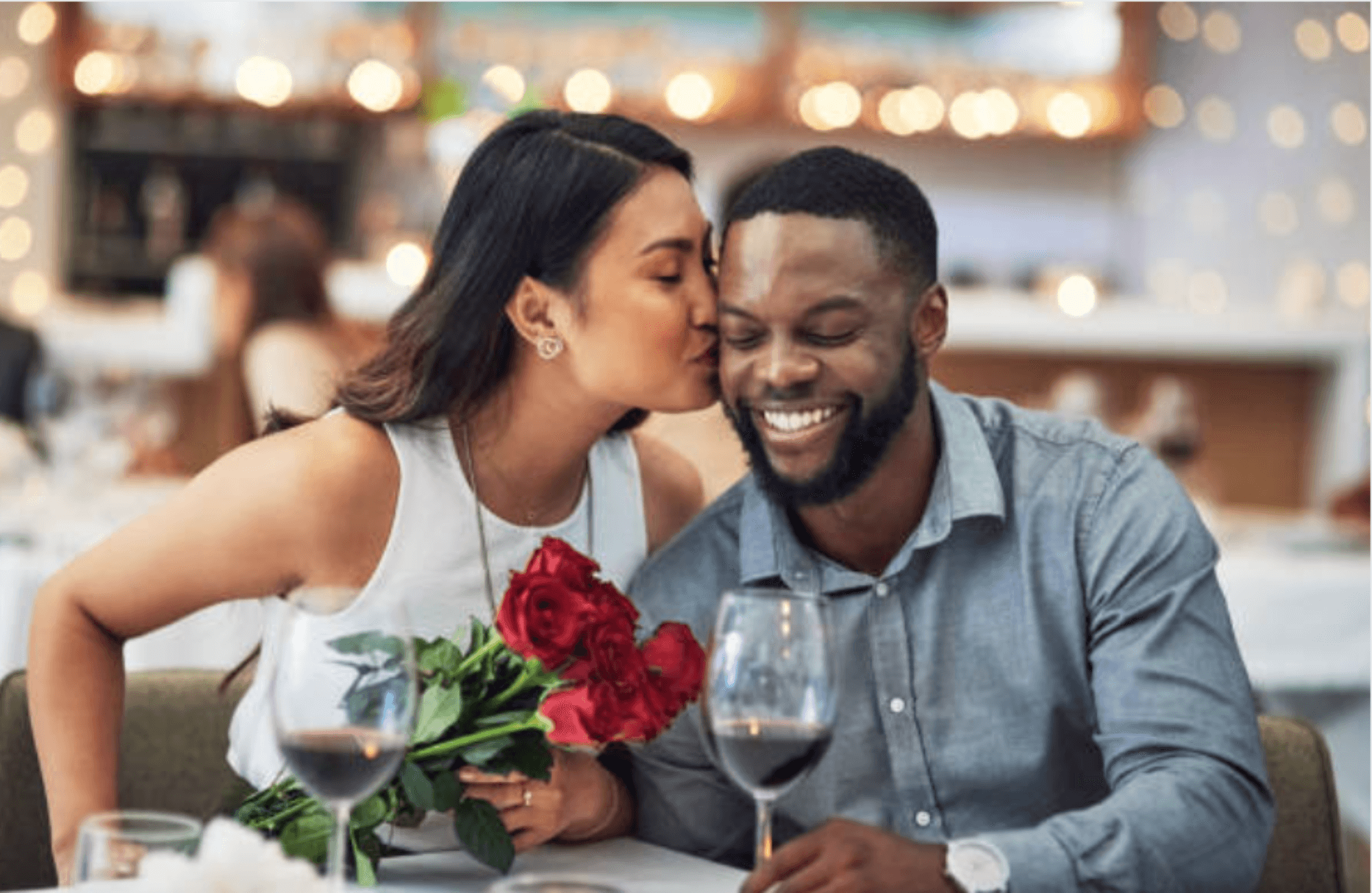 woman kisses man while holding flowers Valentine's Day gift boxes